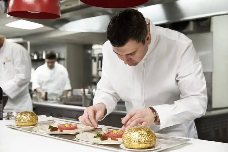 Chef Sébastien Giannini plating dishes in a luxury hotel kitchen