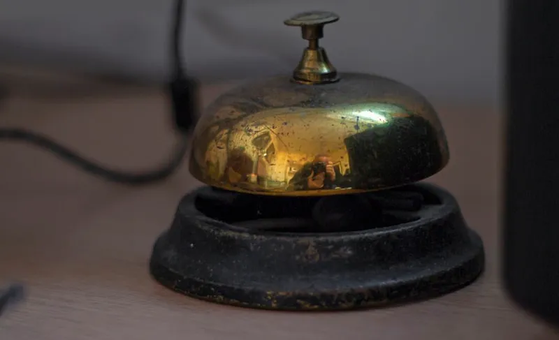 A vintage brass service bell on a concierge desk