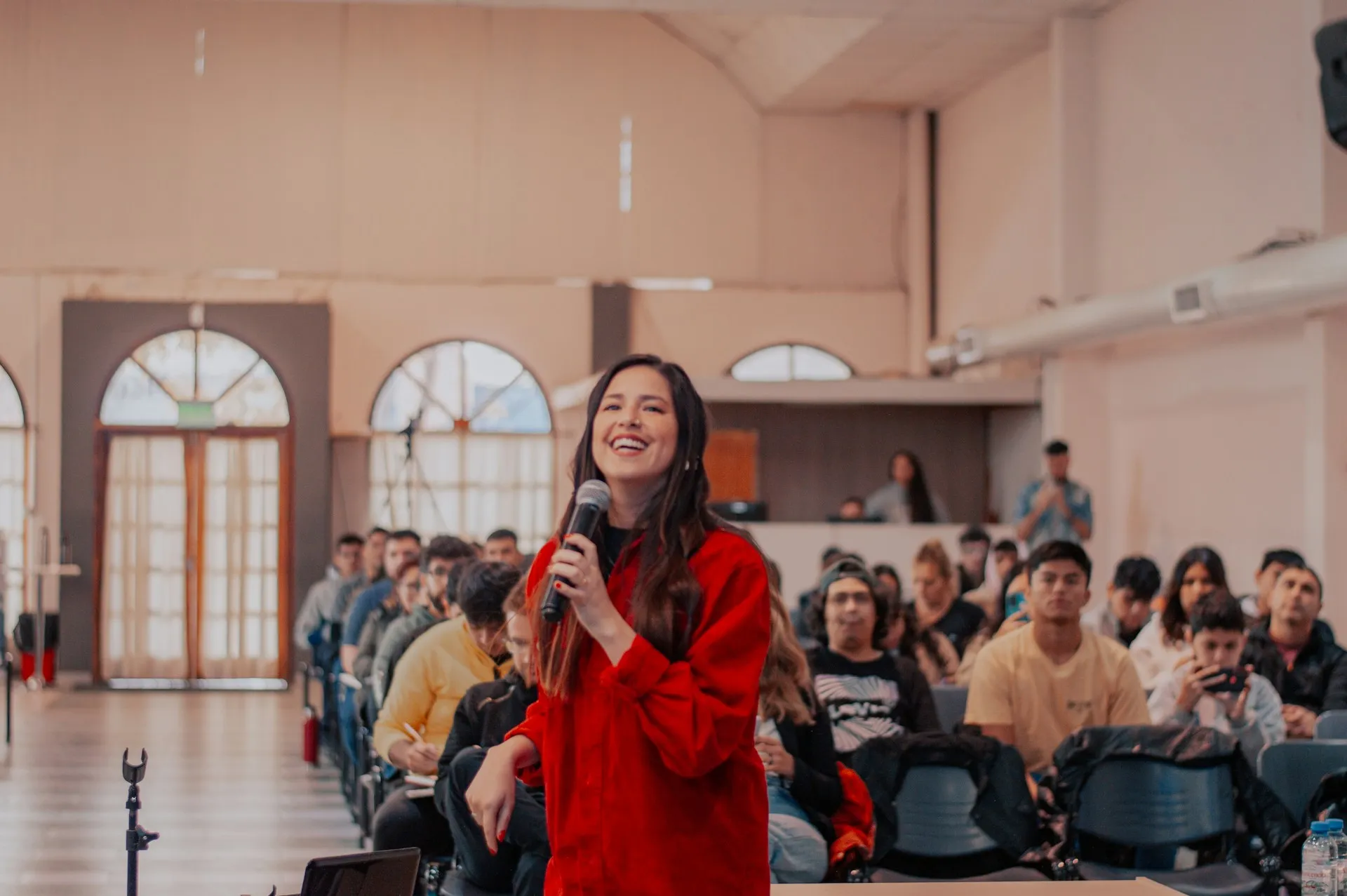 A speaker holding a microphone in front of a seated audience