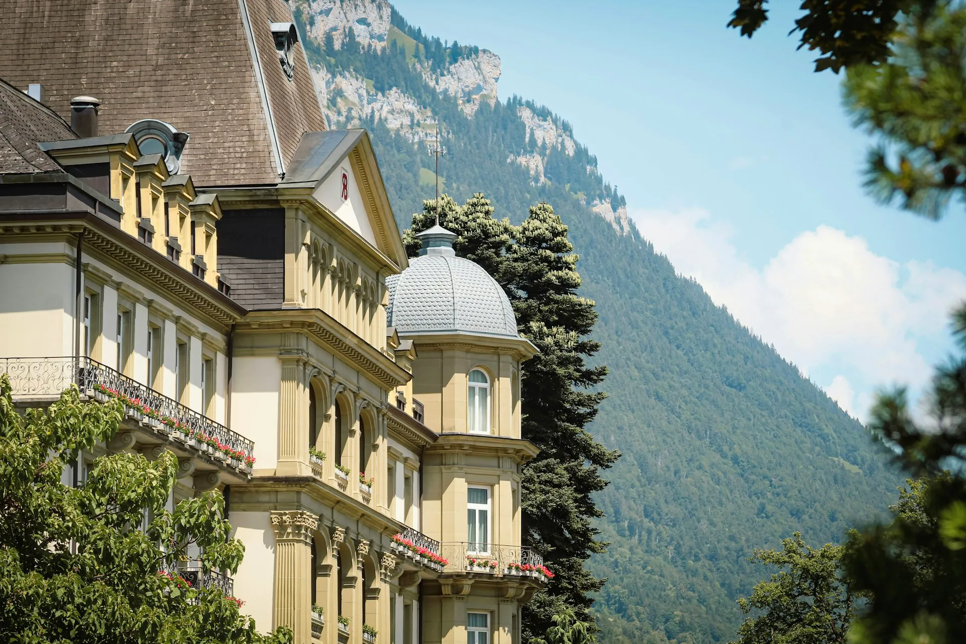 A historic grand hotel with a domed tower against the mountains